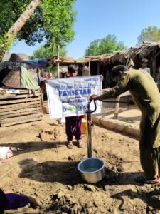 A man draws water from a new well marked Water for Life Pakistan